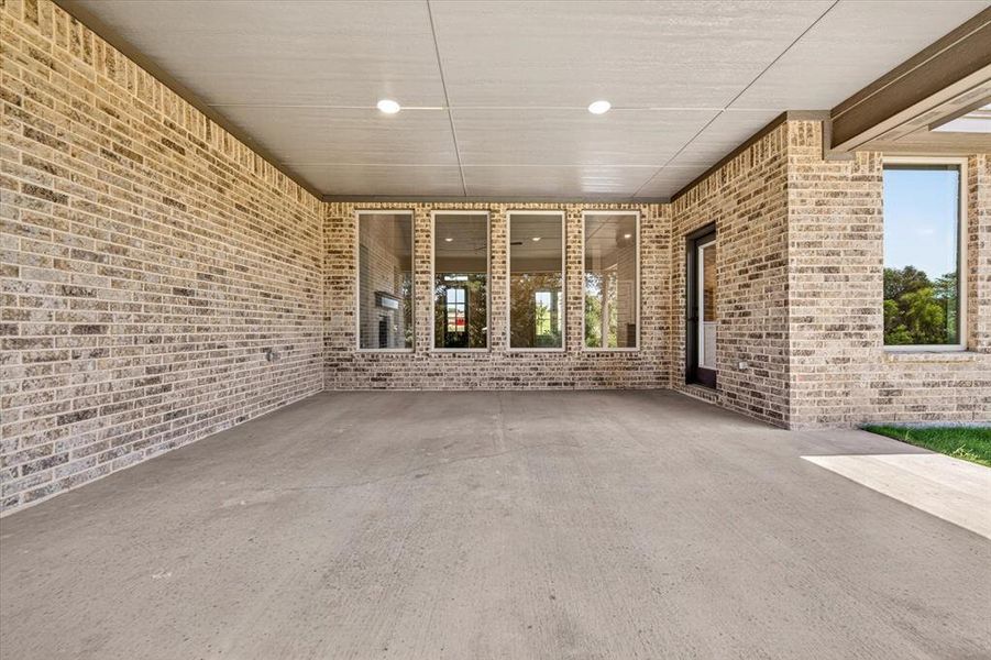 Covered patio featuring a light-toned brick facade and recessed lighting