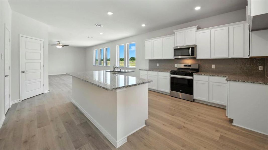 Kitchen featuring white cabinets, light stone counters, stainless steel appliances, and recessed lighting