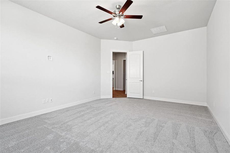 Empty room with light colored carpet and a ceiling fan