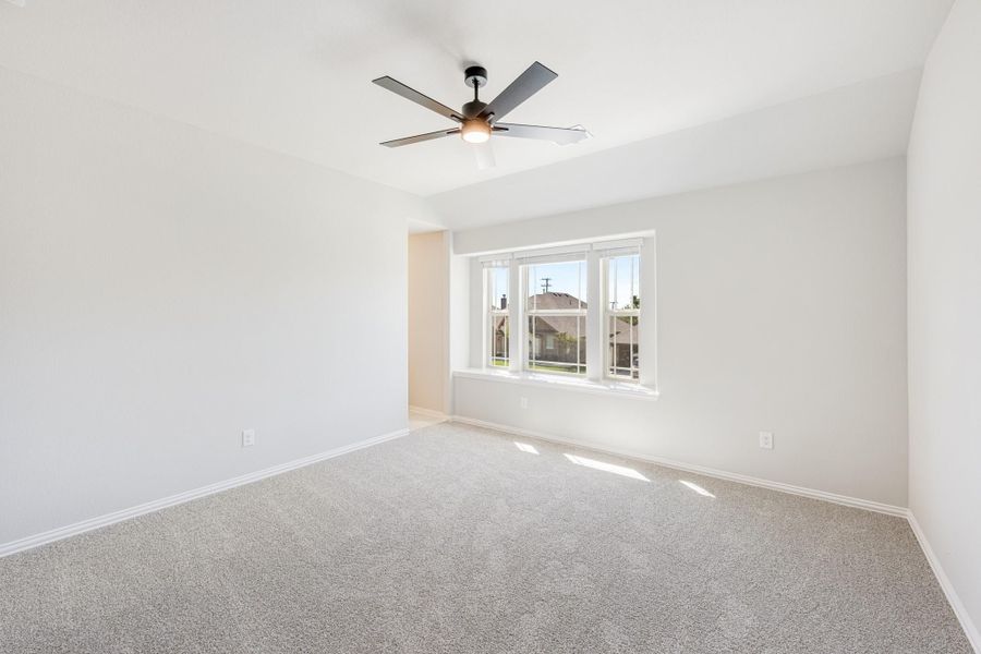 Empty bedroom with vaulted ceiling, ceiling fan, carpet flooring, and triple window with natural light Empty bedroom with vaulted ceiling, ceiling fan, carpet flooring, and triple window with natural light