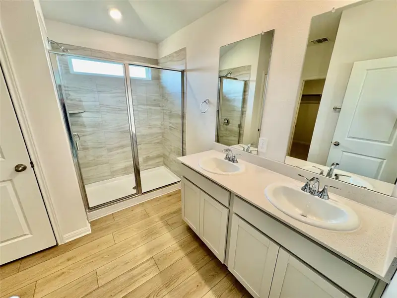 Full bathroom featuring wood finished floors, a stall shower, and double vanity Full bathroom featuring wood finished floors, a stall shower, and double vanity