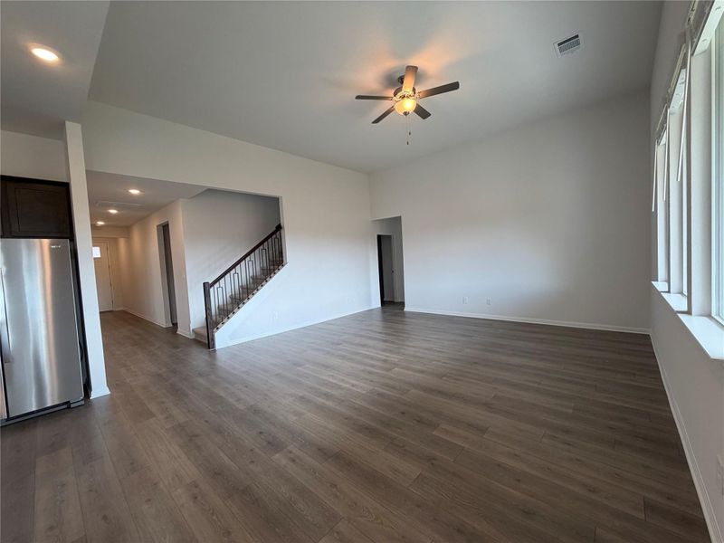 Unfurnished living room featuring dark wood-type flooring, recessed lighting, a ceiling fan, and stairway
