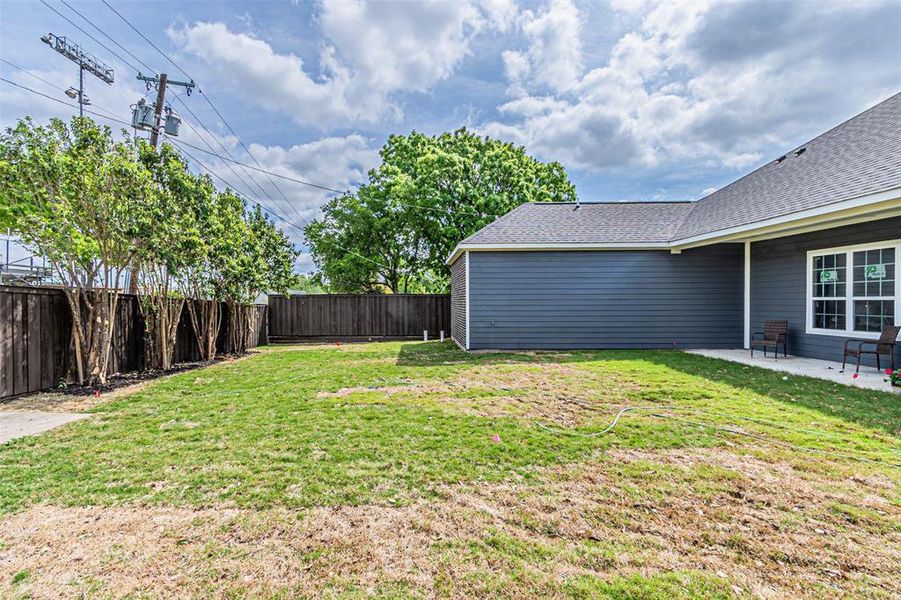 Expansive backyard featuring a privacy fence, mature trees, and a concrete patio