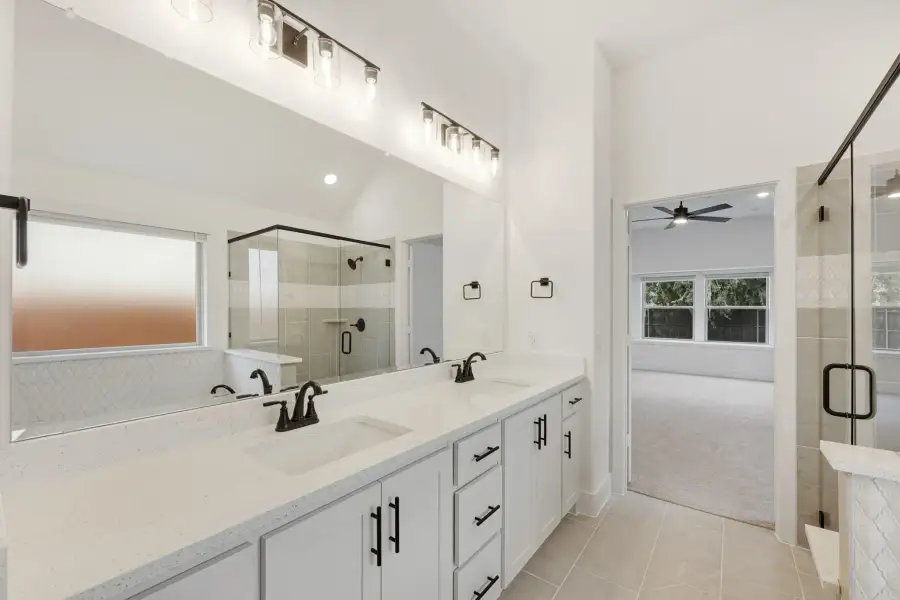 Master bathroom with double vanity, quartz countertops, black fixtures, and glass walk-in shower