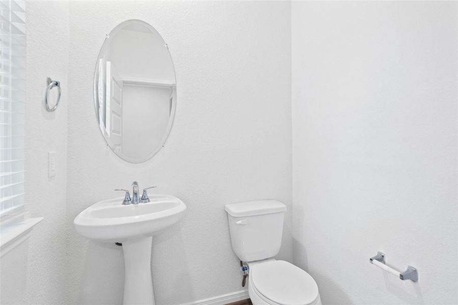 The powder room on the first floor includes a pedestal sink, mirror, and toilet.