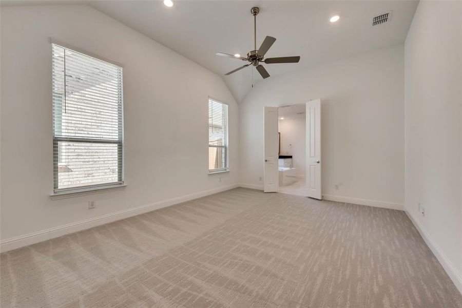 Spare room featuring ceiling fan, lofted ceiling, and light carpet