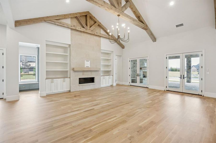 Family room with truss beams, buff lueders stone fireplace surround, & doors to large covered patio.  Hall leads to mud with storage and private office