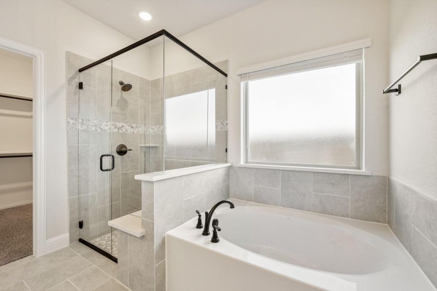 Master bathroom with soaking tub, glass-enclosed tile shower, and walk-in closet access Master bathroom with soaking tub, glass-enclosed tile shower, and walk-in closet access