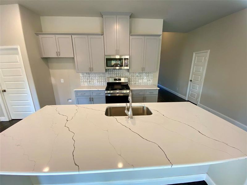 Close up of enormous kitchen island with Monet Quartz counters and lots of seating space for your family & guests