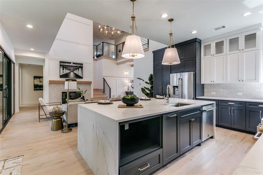 Kitchen featuring stainless steel appliances, light stone counters, backsplash, and light wood-type flooring