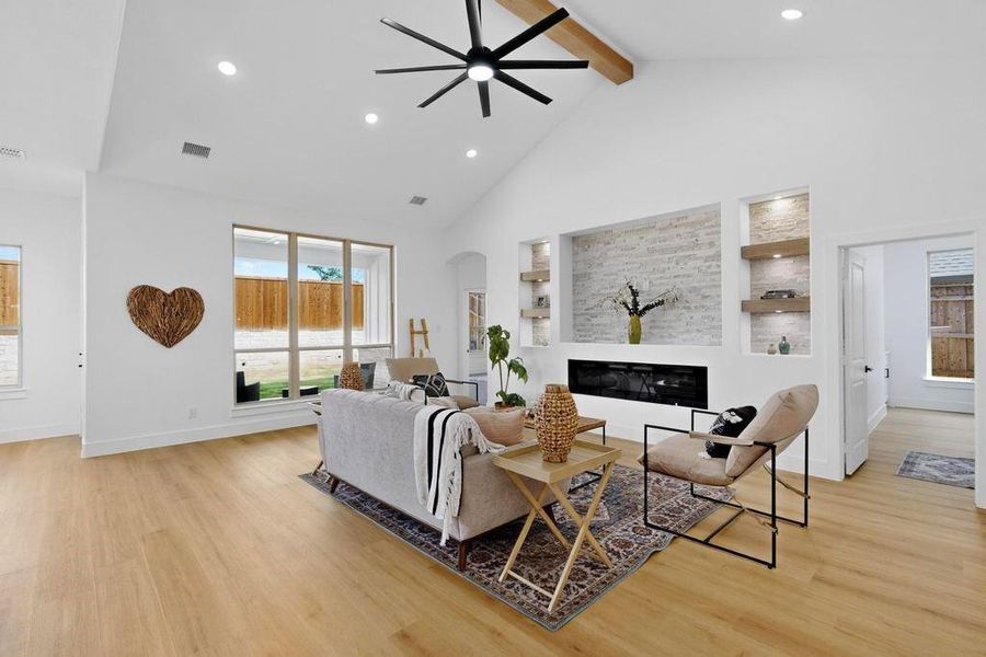 Living area featuring recessed lighting, high vaulted ceiling, beamed ceiling, light wood-style flooring, and arched walkways