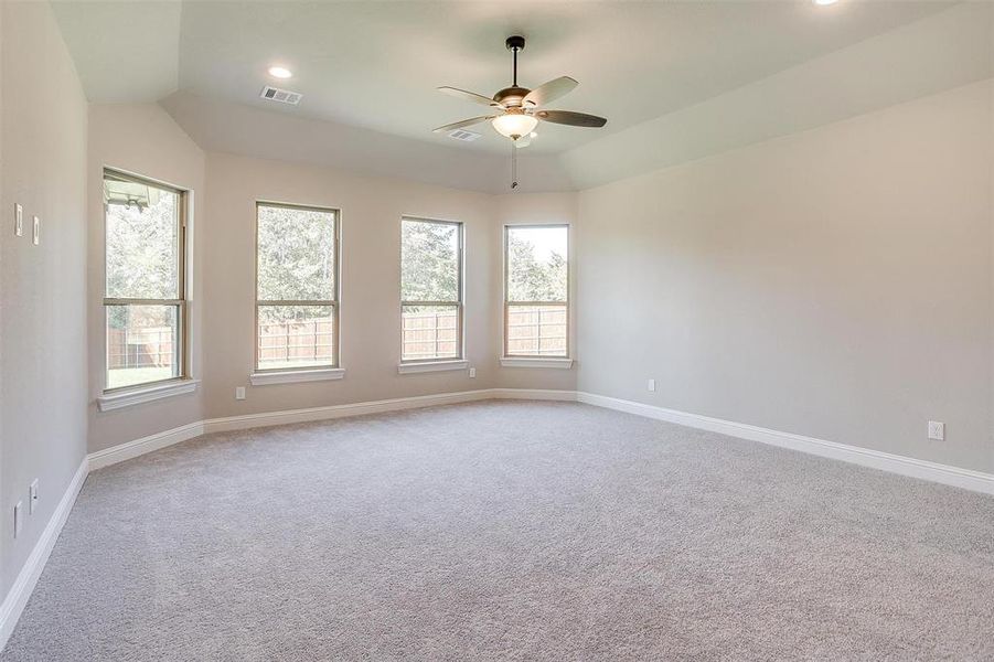 Carpeted empty room with vaulted ceiling and ceiling fan