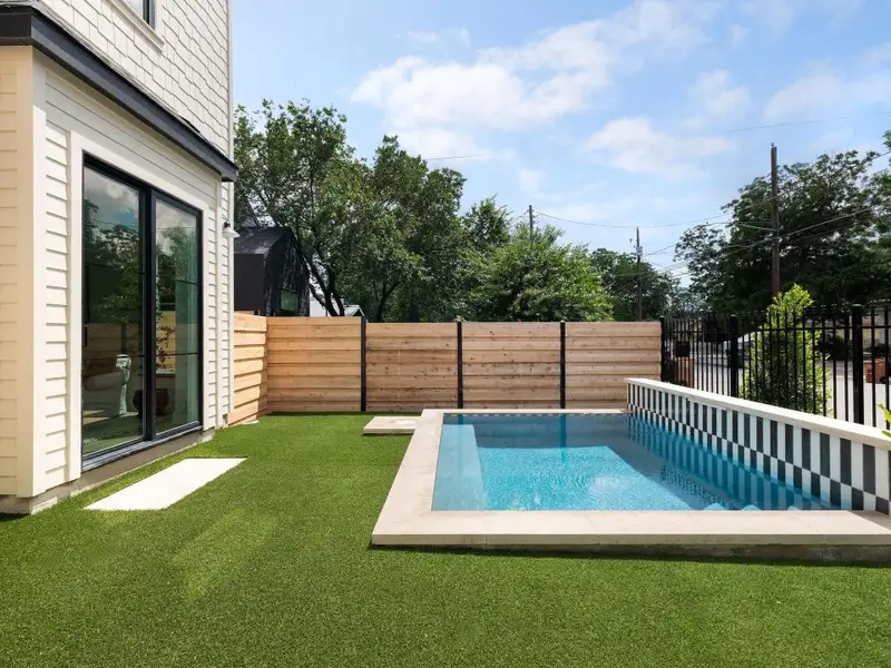 An inviting private pool beckons, surrounded by neatly manicured green space and contemporary fencing.