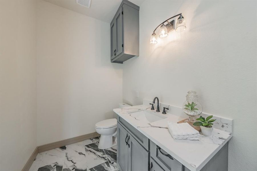 Half bathroom with vanity and light marble finish floors