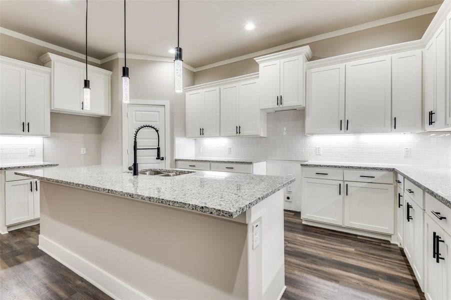 Kitchen with ornamental molding, tasteful backsplash, recessed lighting, light stone countertops, and dark wood finished floors