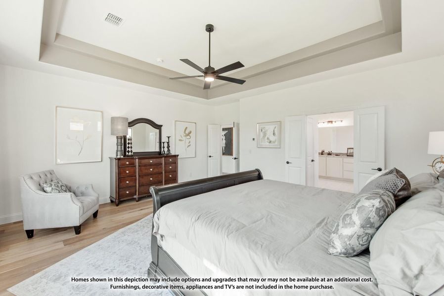 Master bedroom with tray ceiling, ceiling fan, hardwood floors, and ensuite bathroom doorway visible.