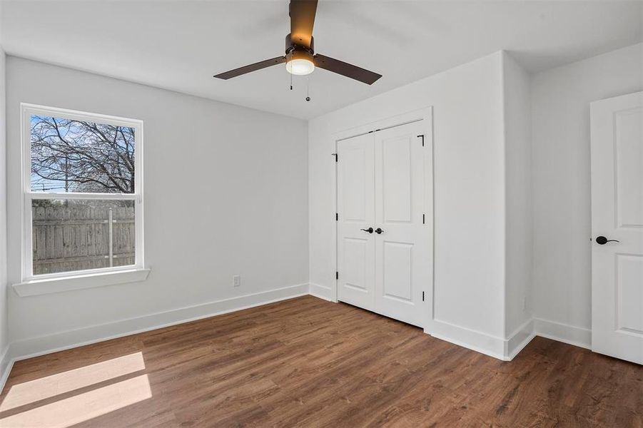 Unfurnished bedroom with a closet, a ceiling fan, baseboards, and wood finished floors