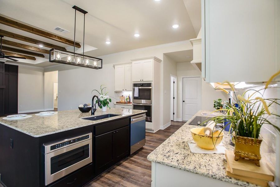 Kitchen with a center island with sink, white cabinets, light stone countertops, dark wood-type flooring, and double oven Kitchen with a center island with sink, white cabinets, light stone countertops, dark wood-type flooring, and double oven