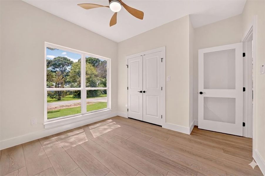 Bright interior featuring wood-finish flooring, a contemporary ceiling fan, and a large window