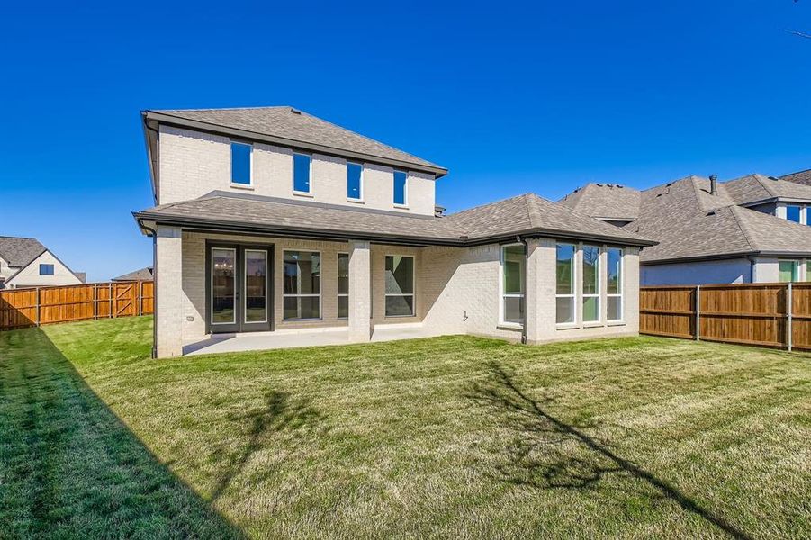 Rear view of house with brick siding, a patio area, a shingled roof, and a fenced backyard