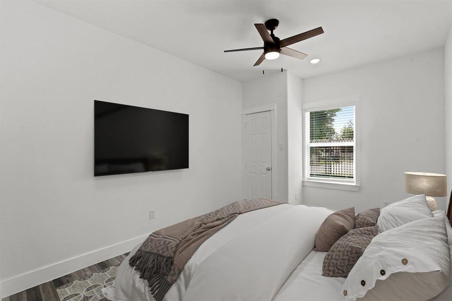 Virtually Staged: Secondary bedroom located in the front of the house, featuring neutral paint, new vinyl floors, a built-in closet, recessed lighting, and a ceiling fan.