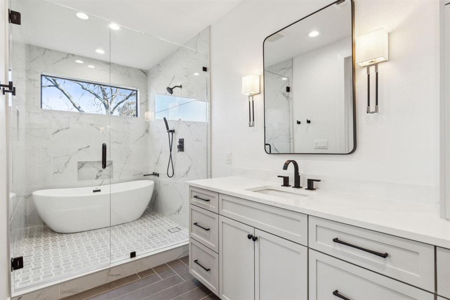 Spa-inspired bathroom with freestanding tub, glass-enclosed shower, and sleek vanity with modern finishes.