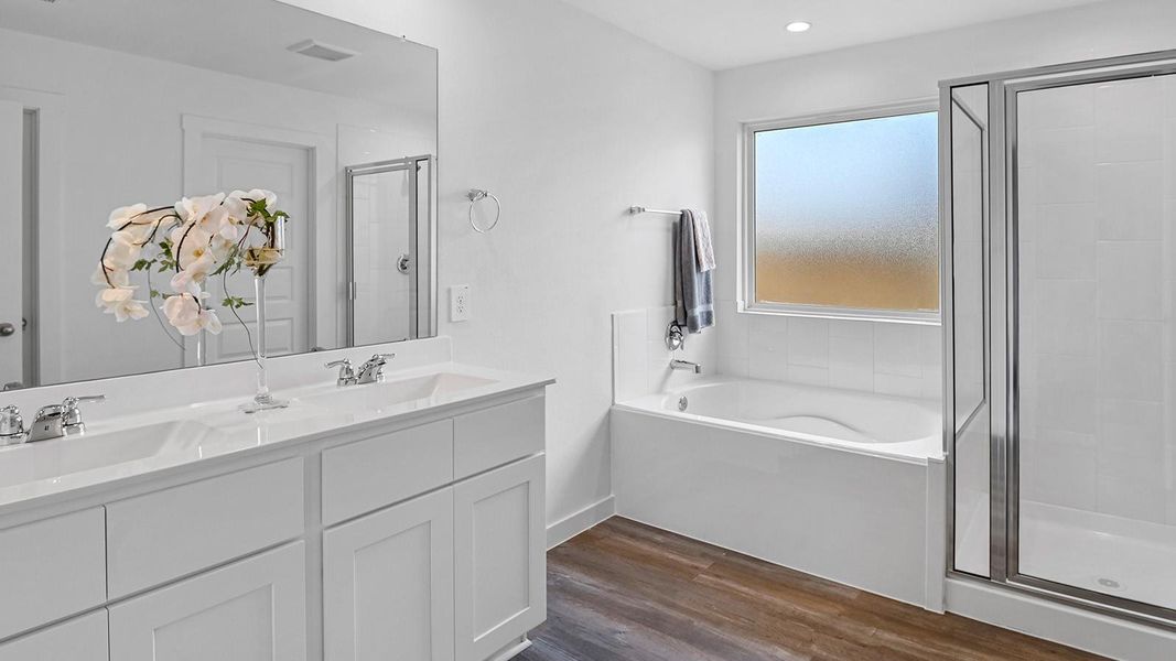 Modern primary bathroom with double vanities, granite countertops, and a glass-enclosed shower with a walk-in closet.