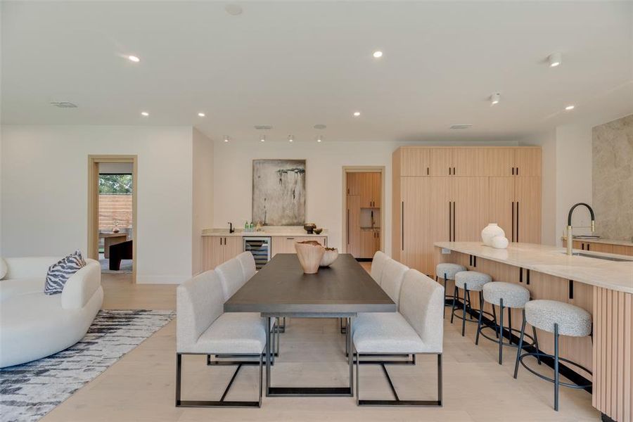 Dining area featuring wine cooler, sink, and light hardwood / wood-style flooring