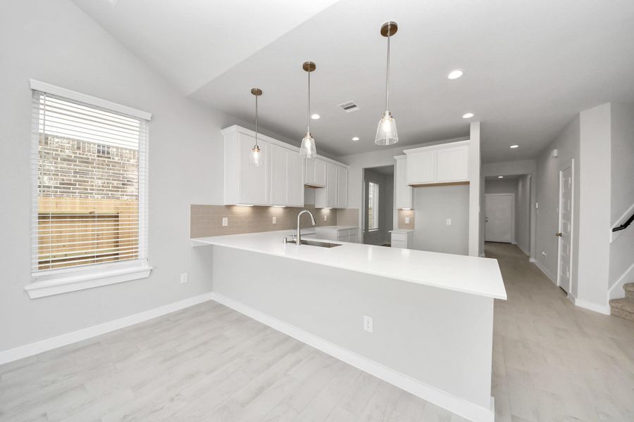 This kitchen is truly a chef's dream! This haven Boasts high ceilings, recessed & pendant lighting, stained wood cabinets, granite countertops, stainless steel appliances, a modern tile backsplash.  All of this overlooks your expansive family room, creating a perfect space for culinary delights and family gatherings.
