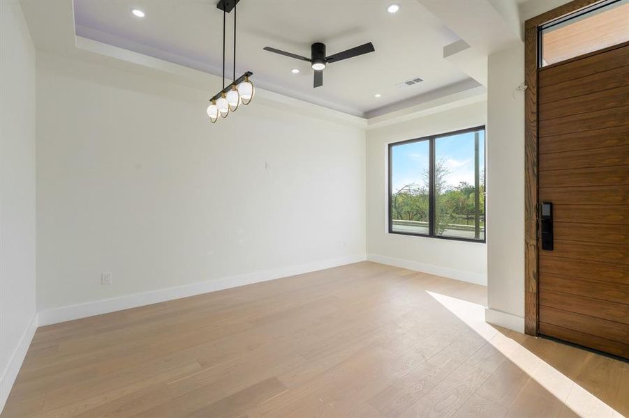 Spare room with a tray ceiling, light wood finished floors, a ceiling fan, and recessed lighting Spare room with a tray ceiling, light wood finished floors, a ceiling fan, and recessed lighting