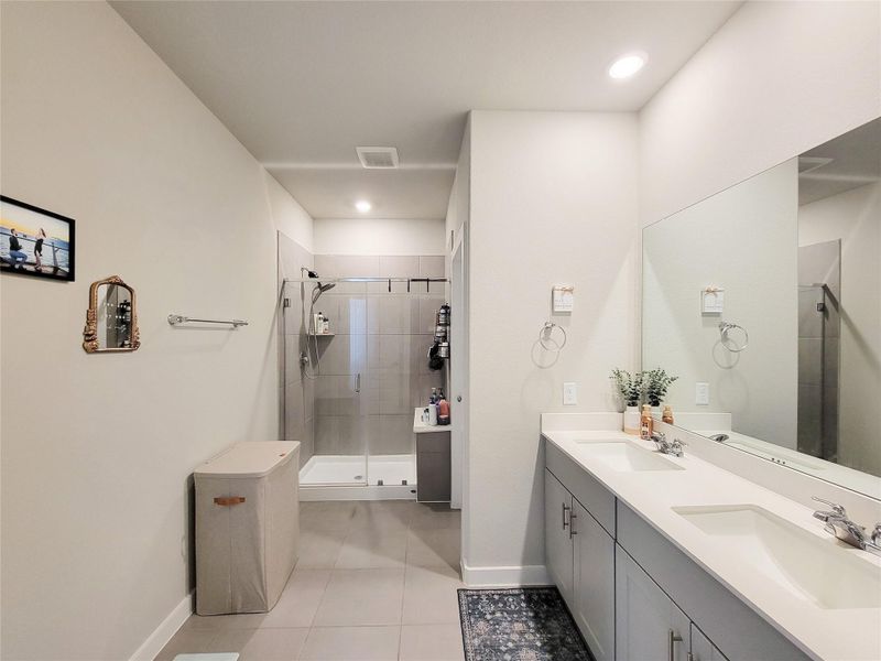 This bathroom features a spacious layout with a large double vanity and modern fixtures. It includes a sizable walk-in shower with glass doors, ample storage, and neutral color tones for a bright, inviting atmosphere.