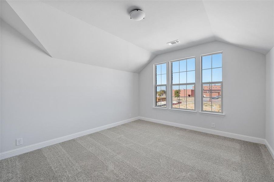 Additional living space with light carpet and vaulted ceiling