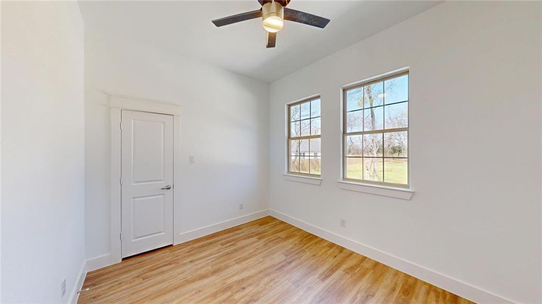 Empty room featuring light wood-type flooring, baseboards, and a ceiling fan