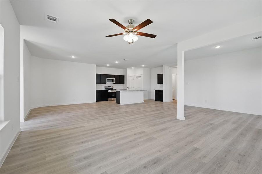 Unfurnished living room with light wood-type flooring, a ceiling fan, visible vents, and recessed lighting Unfurnished living room with light wood-type flooring, a ceiling fan, visible vents, and recessed lighting