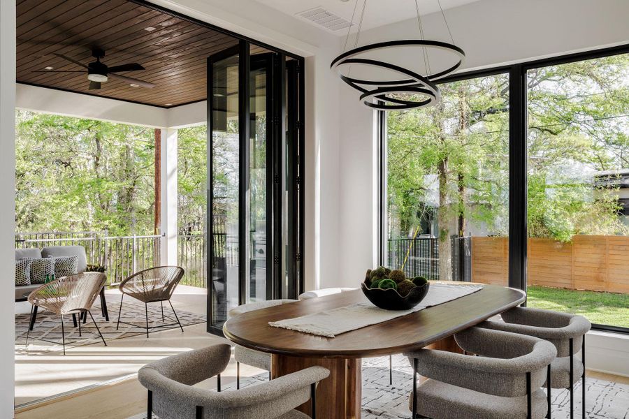 The dining area is surrounded by glass, offering a light-filled setting with views of mature trees and the greenbelt beyond. The dining area is surrounded by glass, offering a light-filled setting with views of mature trees and the greenbelt beyond.