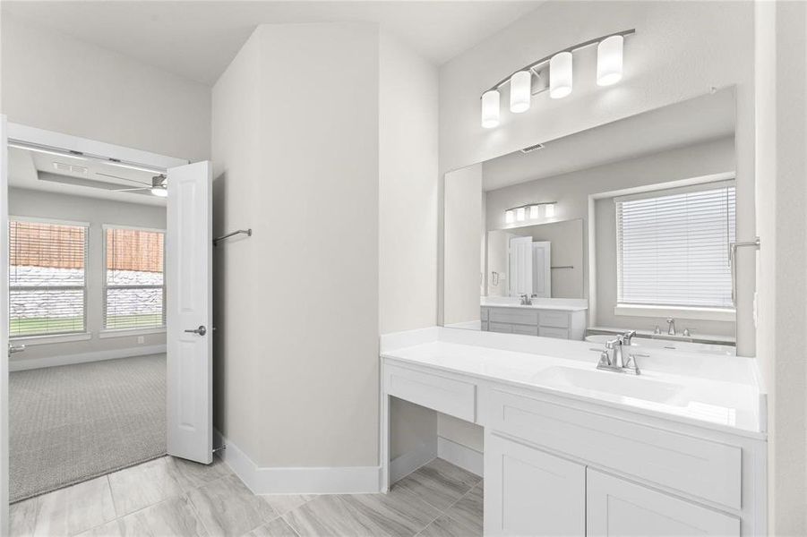 Bathroom featuring a double vanity with white cabinetry, integrated sinks, and chrome faucets Bathroom featuring a double vanity with white cabinetry, integrated sinks, and chrome faucets