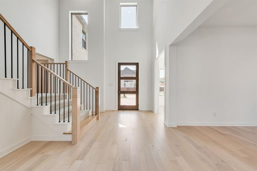 Entrance foyer featuring light wood finished floors, a towering ceiling, and stairs Entrance foyer featuring light wood finished floors, a towering ceiling, and stairs