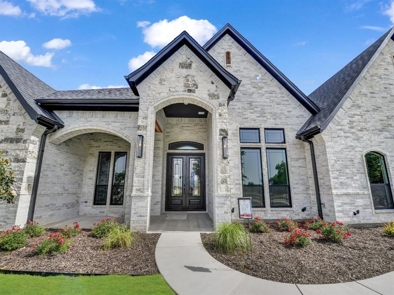 Property entrance featuring french doors, brick siding, and roof with shingles Property entrance featuring french doors, brick siding, and roof with shingles