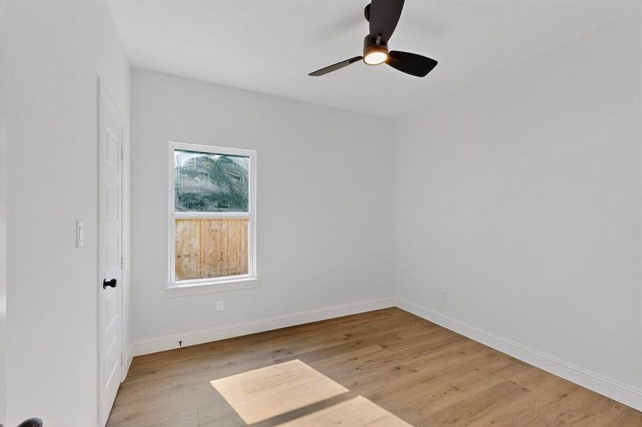 Empty room featuring light wood finished floors and a ceiling fan