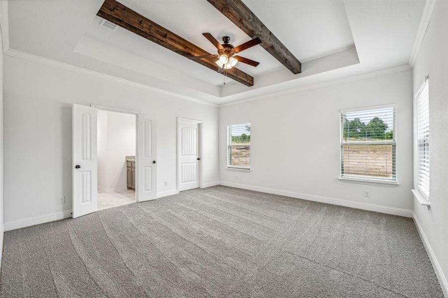 Unfurnished bedroom featuring beam ceiling, ceiling fan, crown molding, and a tray ceiling