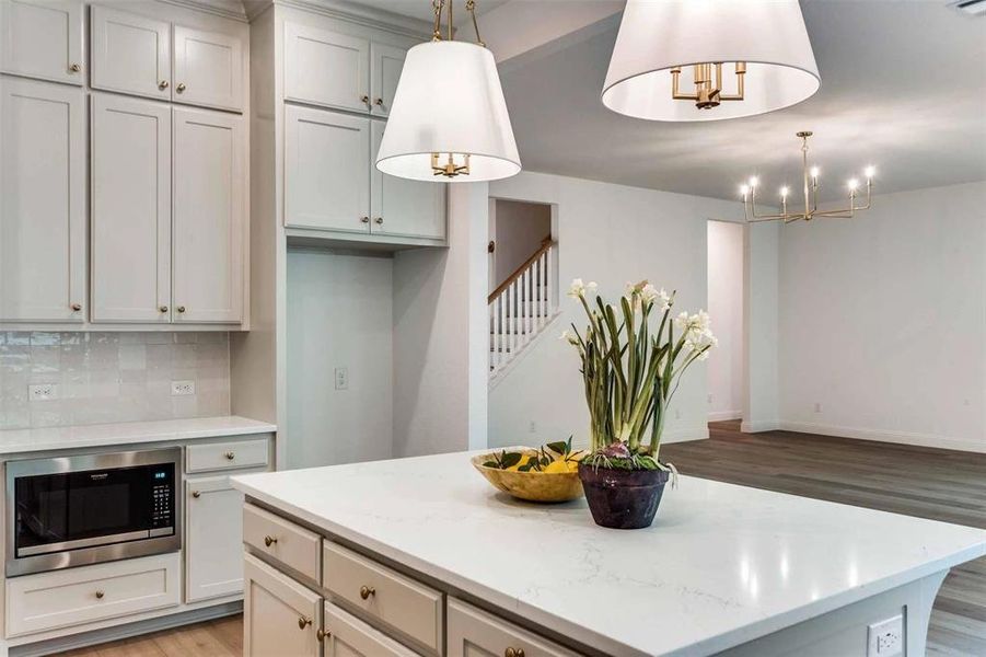 Kitchen featuring stainless steel microwave, light wood-type flooring, a center island, and tasteful backsplash
