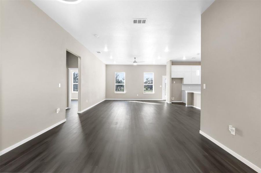 Unfurnished living room featuring dark wood-type flooring and ceiling fan