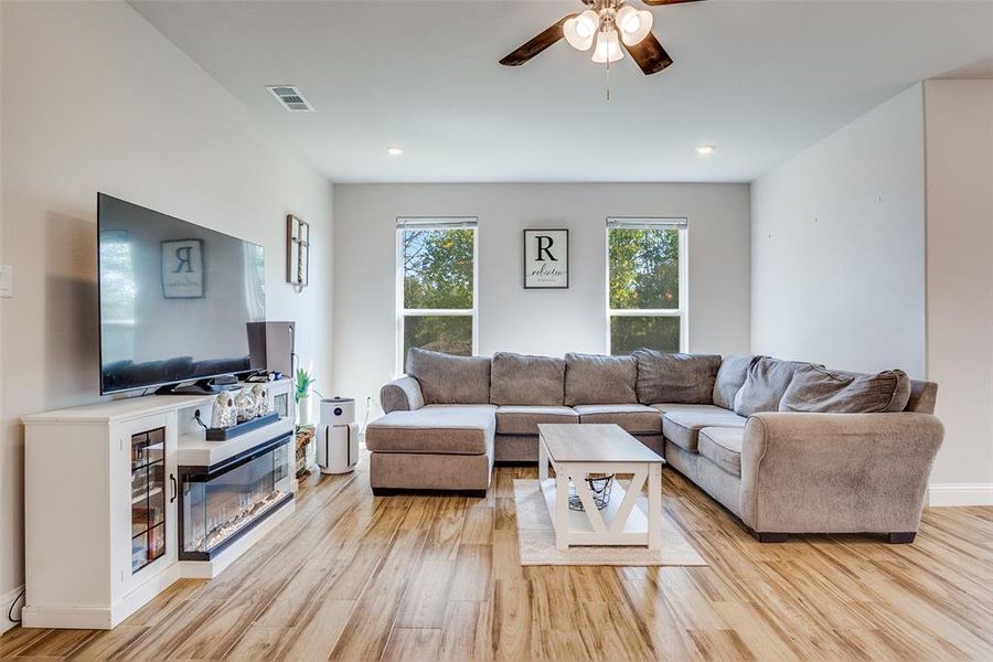 Living room featuring light wood finished floors, a ceiling fan, and recessed lighting