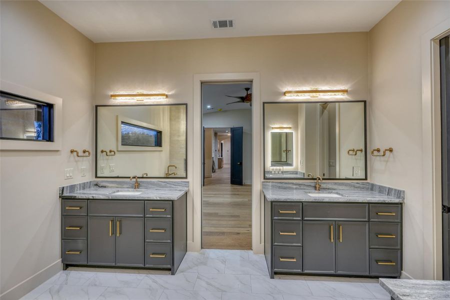 Spa-inspired bath with dual vanities, soaking tub, large walk-in shower, makeup station & custom fixtures.
