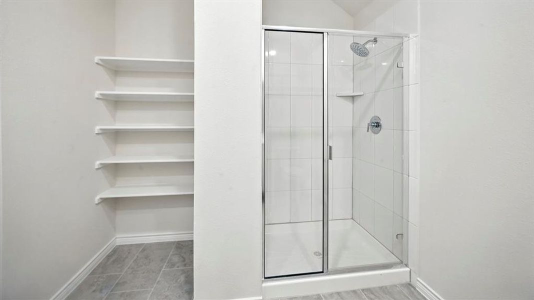 Full bathroom featuring a shower stall and baseboards