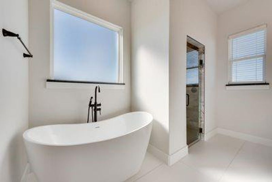 Bathroom featuring tile patterned flooring, a healthy amount of sunlight, and separate shower and tub