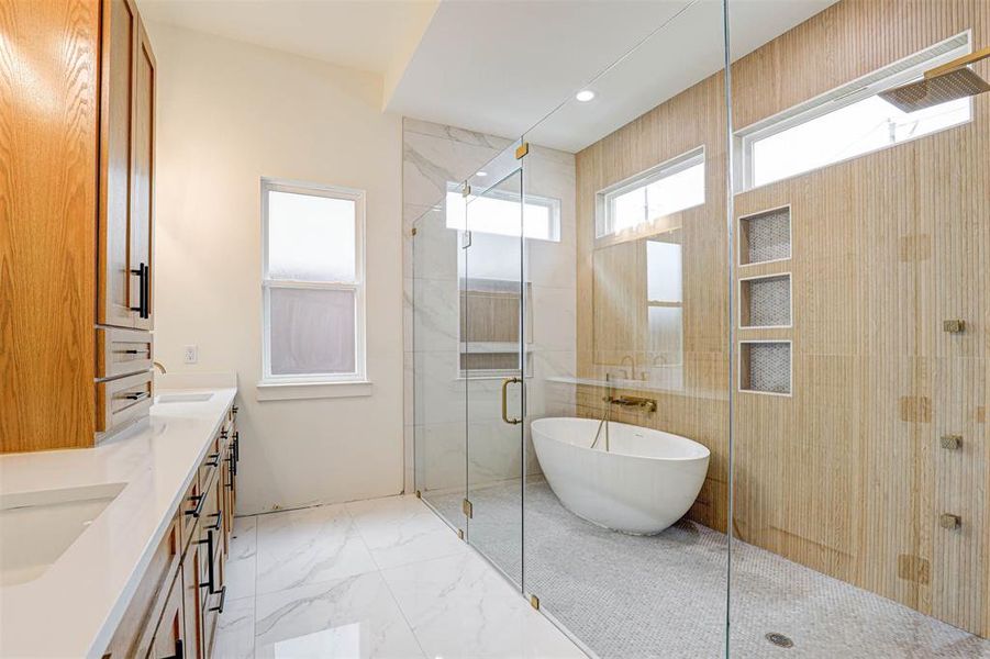 Full bathroom with a stall shower, a freestanding tub, double vanity, marble finish flooring, and recessed lighting