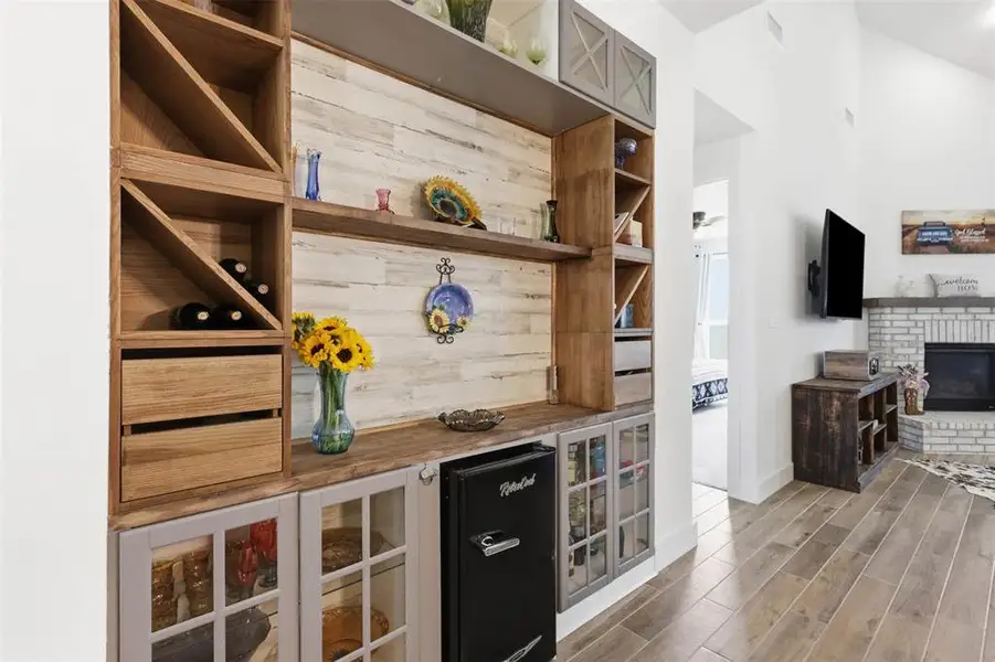Built-in wet bar featuring a wood-finish countertop, shiplap-style backsplash, integrated wine storage, and glass-front cabinetry