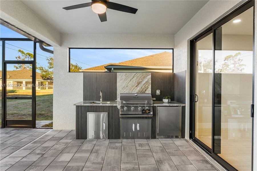 FULLY EQUIPED OUTDOOR KITCHEN w/ BUILT-IN stainless steel BBQ GRILL, SINK, BEVERAGE REFRIGERATOR, GRANITE COUNTERTOPS & MODERN BACKSPLASH, ideal for OUTDOOR DINING & ENTERTAINING!