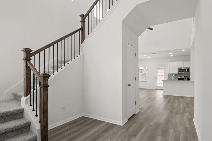 Stairway with wood finished floors, recessed lighting, and a high ceiling Stairway with wood finished floors, recessed lighting, and a high ceiling
